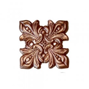 May include: A square, copper-colored decorative tile with a floral design. The tile has a raised, ornate pattern with a central diamond shape.