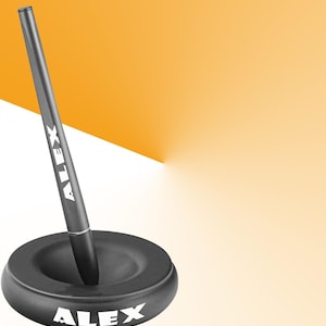 以下が含まれることがあります： 「ALEX」と印刷された黒いペン立てと、側面に同じ名前が印刷された黒いペン