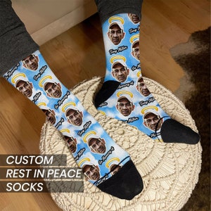May include: A pair of custom socks with a blue and white cloud pattern. The socks feature a repeated image of a person with a halo, and the text "In Memory of" and "Tony Miller".