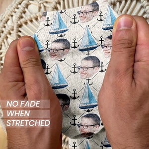 May include: White socks with a repeating pattern of blue sailboats, anchors, and a person's face. The text "NO FADE WHEN STRETCHED" is printed on the socks.