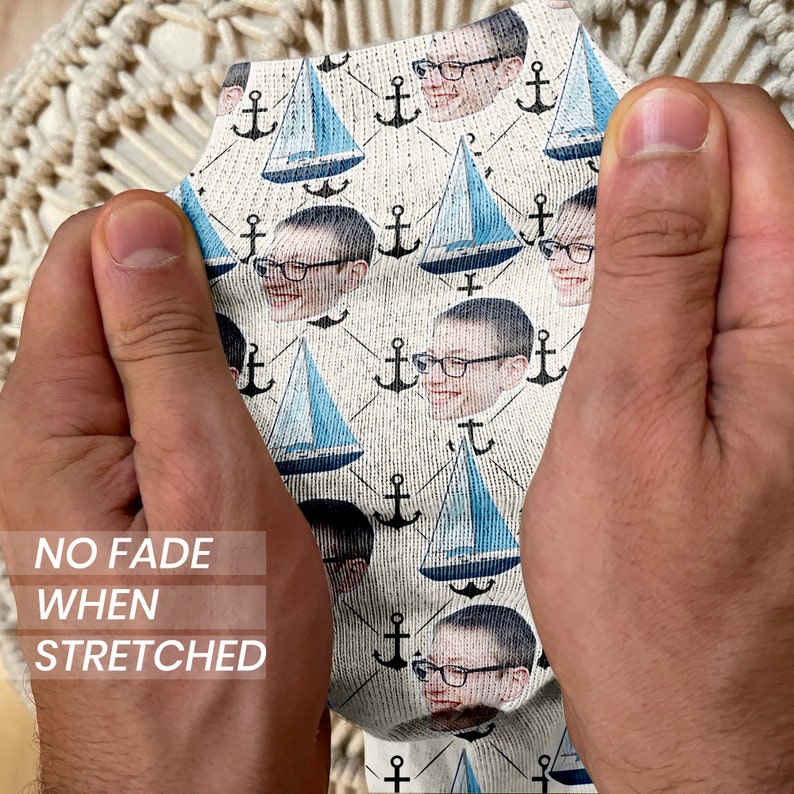 May include: White socks with a repeating pattern of blue sailboats, anchors, and a person's face. The text "NO FADE WHEN STRETCHED" is printed on the socks.