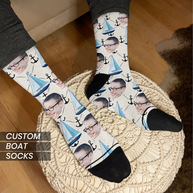 May include: A pair of white socks with a blue sailboat and anchor pattern. The socks feature a repeated image of a person's face.