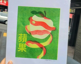 May include: Print of a stylized apple with a peeled spiral, set against a green background. The apple features red and white stripes, with the Chinese characters for "apple" in yellow. The print is held in a clear plastic sleeve.