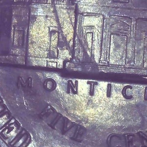 May include: Close-up of a United States nickel coin. The coin features an image of Monticello, the home of Thomas Jefferson, and the words "MONTICELLO", "FIVE CENTS", and "UNITED STATES OF AMERICA".
