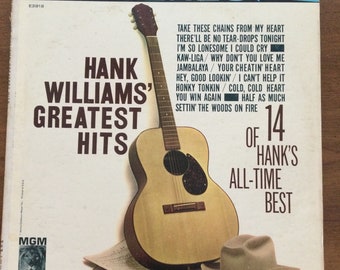 May include: Vintage vinyl record album cover for Hank Williams' Greatest Hits. The cover features a guitar, a cowboy hat, and sheet music. The album includes 14 of Hank's all-time best songs.