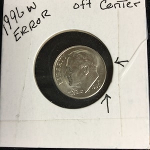 May include: A 1996 W error dime, off-center, displayed in a protective holder. The coin features a profile of a man and the word "LIBERTY". The holder is labeled with the year, "ERROR", and "off Center".