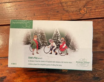 May include: A Department 56 box set titled "Child's Play" featuring a winter scene with three children rolling hoops. The box has a green and white design with text that reads "In Dickens' time the streets of England were always a bit merrier when children played the delightful game of rolling the hoop."
