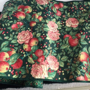 K&ouml;nnte beinhalten: Dunkelgr&uuml;ner Stoff mit einem Muster aus roten &Auml;pfeln, rosa Rosen und roten Beeren. Der Stoff hat einen gr&uuml;nen Rand mit einem kleinen Blumenmuster. Das Design ist ein Vintage-Botanisches Muster, geeignet f&uuml;r verschiedene Bastelprojekte.