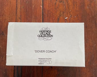 May include: A rectangular, off-white box with the text "HERITAGE VILLAGE COLLECTION" and "DOVER COACH" printed on it. The box also includes the text "Handpainted Porcelain" and the number "6590-0".
