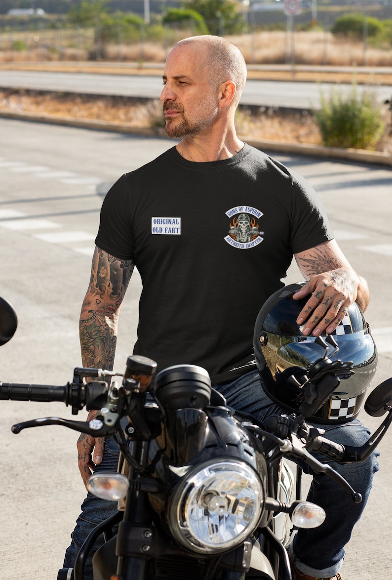 May include: A man wearing a black t-shirt with the text "Original Old Fart" and a patch that says "Sons of Aspirin Arthritis Chapter" is sitting on a black motorcycle.