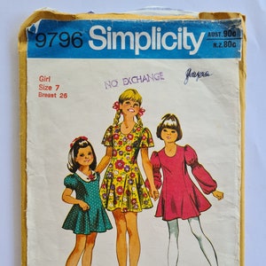 Peut inclure: Ancienne enveloppe de patron de couture Simplicity. L'illustration montre trois filles portant des robes. Le texte comprend "9796 Simplicity", "Girl Size 7 Breast 26" et "NO EXCHANGE".