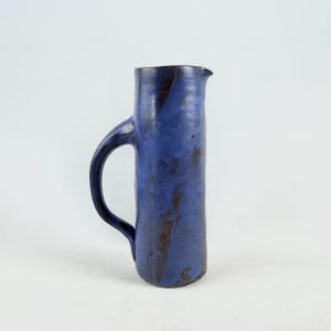 Puede incluir: Jarra de cerámica hecha a mano, con un esmalte azul oscuro y un asa curvada. La jarra tiene un pico vertedor y mide aproximadamente 25 cm de altura.