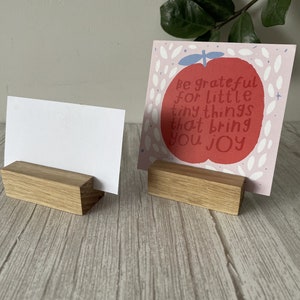 May include: Two wooden card holders with blank cards. The card holder on the right has a pink card with a red apple illustration and the text "Be grateful for little tiny things that bring you joy".