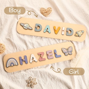 Może przedstawiać: Dwa drewniane puzzle z kolorowymi literami, kt&oacute;re układają się w imiona "DAVID" i "HAZEL". Puzzle "DAVID" ma rakietę i planetę, a puzzle "HAZEL" ma motyla i tęczę.
