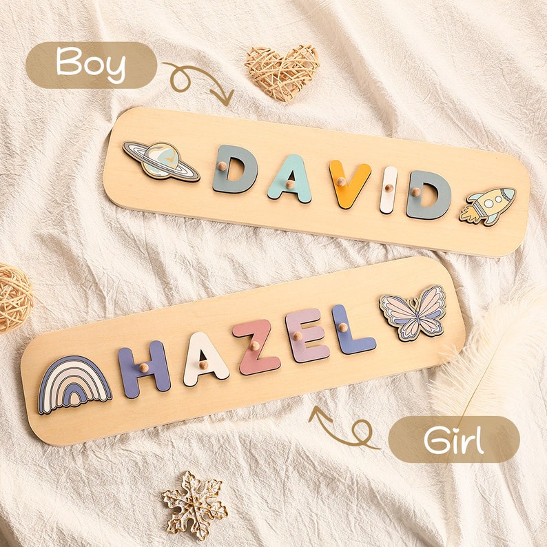 Może przedstawiać: Dwa drewniane puzzle z kolorowymi literami, kt&oacute;re układają się w imiona "DAVID" i "HAZEL". Puzzle "DAVID" ma rakietę i planetę, a puzzle "HAZEL" ma motyla i tęczę.