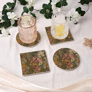 Puede incluir: Cuatro posavasos florales en formas cuadradas y redondas, con dos vasos encima. Los posavasos presentan un colorido estampado floral con flores rosas, amarillas y azules sobre un fondo verde. Los vasos son transparentes y texturizados.