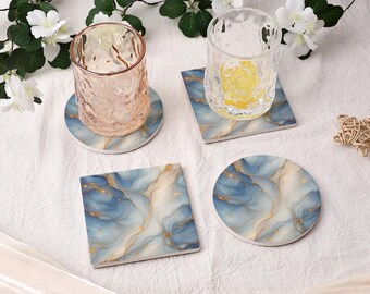 May include: A set of four coasters featuring a blue, white, and gold marbled pattern. Two coasters are square and two are circular. Two clear, textured glass tumblers sit on top of the coasters, one containing a yellow liquid.