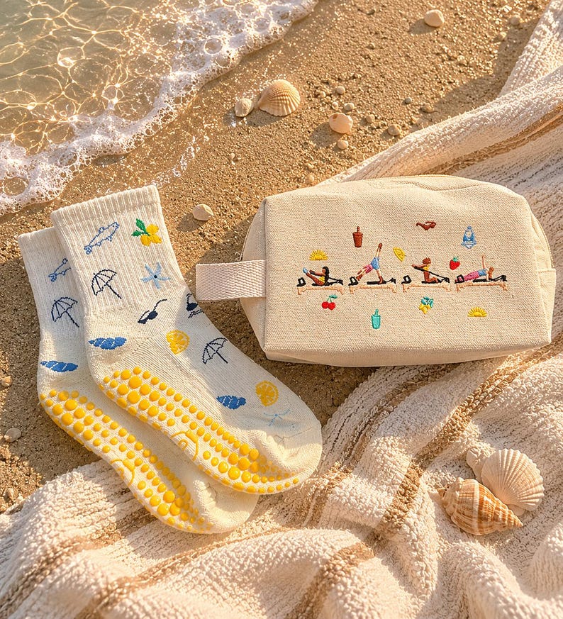 May include: A pair of cream-colored socks with blue umbrellas, clouds, and lemons, and a beige cosmetic bag with embroidered figures doing yoga. The socks have yellow non-slip grips on the soles. The bag has a small handle.