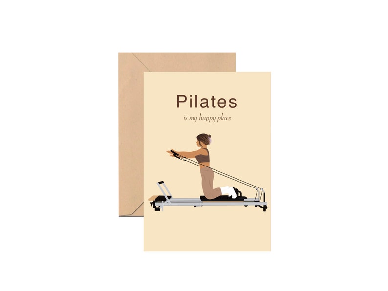 May include: A greeting card with a beige background and a Pilates theme. The card features an illustration of a person exercising on a Pilates reformer machine. The text "Pilates is my happy place" is printed on the card. A brown envelope is behind the card.
