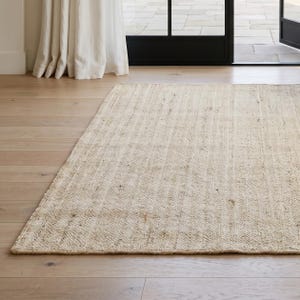 May include: A rectangular area rug featuring a woven, textured surface in a light beige, natural tan color. The rug displays a consistent, tight weave pattern with subtle variations in fiber tone, creating a neutral, earthy appearance across the floor.