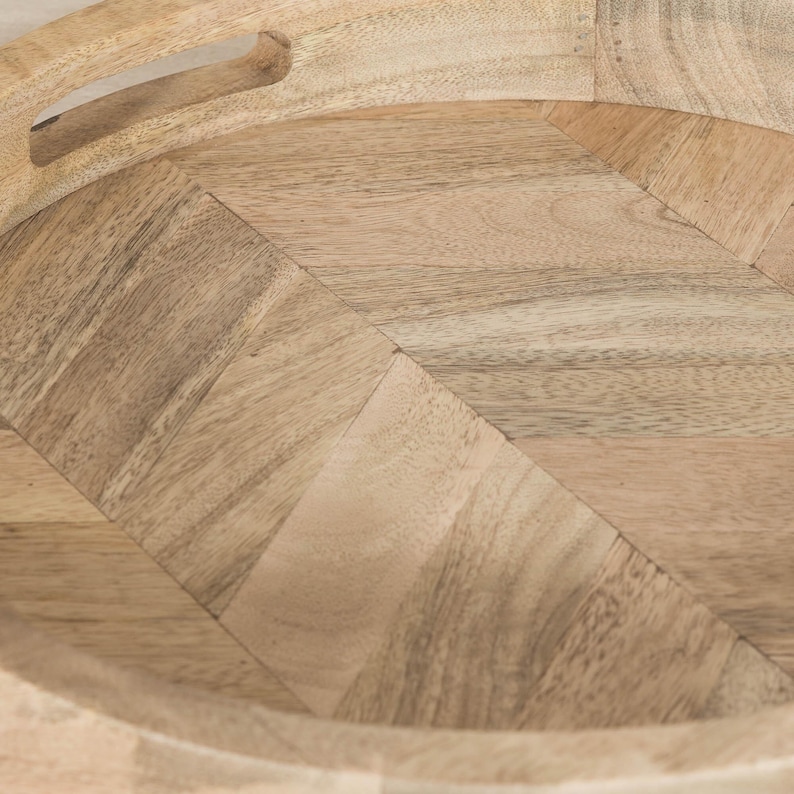 May include: A round wooden tray with a herringbone pattern. The tray has a natural wood finish and a raised edge.