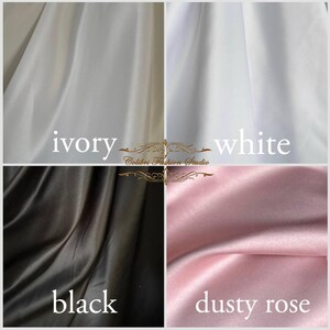 Classic ivory dress for a flower girl. The dress is made of satin. The top is decorated with pearls along the neckline and has satin sleeves. The skirt is satin and floor length. The back of the dress is complemented by a satin bow.