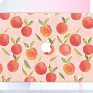 Könnte beinhalten: Eine rosa Laptop-Haut mit einem sich wiederholenden Muster aus Illustrationen von Pfirsichen. Die Haut hat einen weißen Apple-Logo-Ausschnitt.