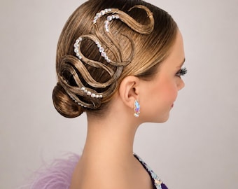 May include: A hairstyle featuring intricate, sculpted brown hair swirls adorned with clear, iridescent crystals. The hair is pulled back into a low bun, and the look is complemented by a single teardrop-shaped earring with a matching iridescent finish.