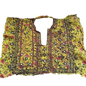 May include: A yellow fabric neckpiece with intricate embroidery and mirror embellishments. The fabric has a floral pattern in red, green, and brown.