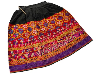 May include: A black skirt with a vibrant, embroidered design. The skirt features a black waistband and a lower section adorned with colorful floral patterns in red, pink, blue, and yellow. The hem is trimmed with a purple border.