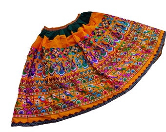May include: A yellow skirt with colorful embroidery featuring birds and floral patterns. The skirt has a green waistband and a black trim.