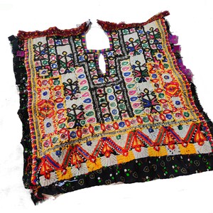 May include: A colorful embroidered fabric panel with a geometric design. The fabric is decorated with mirrors, beads, and sequins. The panel is made of a variety of fabrics, including cotton, silk, and velvet.