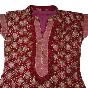 May include: A red embroidered top with a floral pattern and a lace trim around the neckline and sleeves.