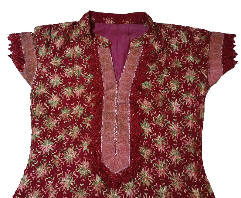 May include: A red embroidered top with a floral pattern and a lace trim around the neckline and sleeves.