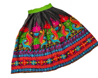 May include: A black skirt with colorful embroidery featuring birds, flowers, and geometric patterns. The skirt has a green waistband and is made of a soft, flowing fabric.