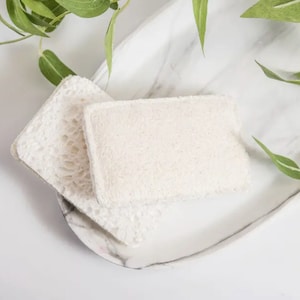 以下が含まれることがあります： 白いロ－フ－スポンジが2つ、重ねて、白い大理石の表面に置かれています。ロ－フ－スポンジは天然繊維でできており、肌の角質除去とクレンジングに最適です。