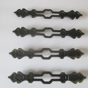 May include: Four antique-style cabinet pulls with a decorative, ornate design. The pulls are made of metal and have a dark bronze finish.