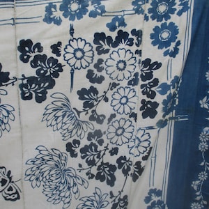 May include: A white fabric with a blue floral pattern. The fabric has a blue border with a white floral pattern. The fabric is folded in half.