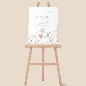 May include: A white sign with the text "Bienvenue au bapt&ecirc;me de Juliette 8 septembre 2023" and a watercolor illustration of flowers and butterflies. The sign is displayed on a wooden easel.