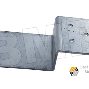 May include: A silver metal bracket with a bend in the middle and four holes on the right side. The bracket is designed for attaching to a wall or other surface.