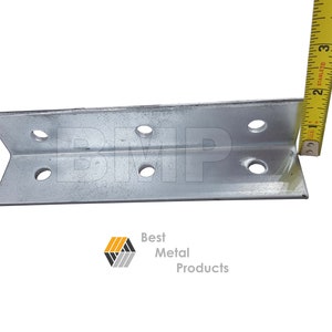 May include: A silver metal angle bracket with eight holes, measuring 2 inches in length. The bracket is being measured with a yellow tape measure.