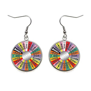 May include: A pair of silver earrings with a colorful wheel of fortune design. The wheel features various dollar amounts, including $5, $30, $300, $500, $700, $900, $1,000, $2,500, $3,000, $4,000, $5,000, $7,500, $8,000, and $10,000. The wheel also includes the phrases "Bankrupt" and "Lose a Turn".