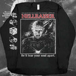 May include: A black long-sleeve shirt featuring a graphic of Pinhead from Hellraiser. The text reads: I have seen the future of horror and his name is Clive Barker. - STEPHEN KING, HELLRAISER, and He'll tear your soul apart. The sleeve has chain icons.