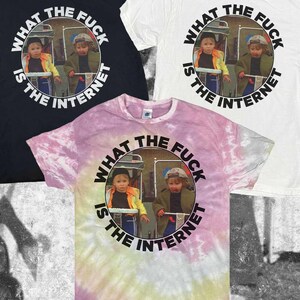 Puede incluir: Tres camisetas de manga corta en negro, blanco y un patrón tie-dye rosa y amarillo. Cada camiseta presenta un gráfico circular de dos niños en cochecitos con el texto "WHAT THE FUCK IS THE INTERNET" impreso en una fuente negra circular.