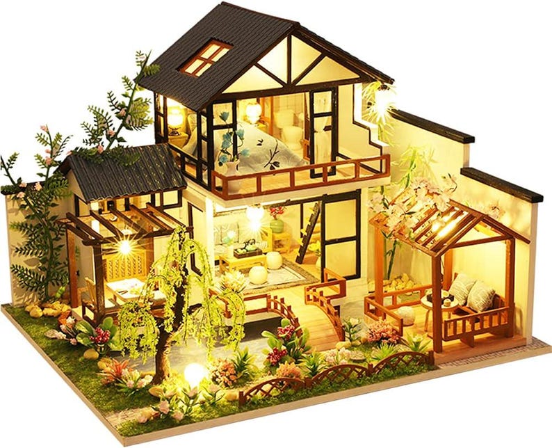 May include: A miniature dollhouse with a two-story design, featuring a brown wooden exterior, a white roof, and a detailed interior with furniture and lighting. The dollhouse is surrounded by a lush green garden with trees and flowers.