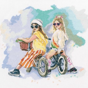 May include: Two girls wearing sunglasses and hats ride toy bikes. One girl wears a yellow shirt and orange and white striped pants. The other girl wears a white shirt with a rainbow stripe and pink socks.