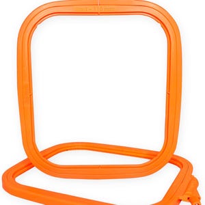 May include: Two orange embroidery hoops. The top hoop is square, with the text "No. 1 - 110 mm" and "35 mm" printed on it. The bottom hoop is also square, and partially visible. The hoops are made of plastic and are designed for holding fabric taut while embroidering.