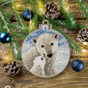May include: A white polar bear and cub are depicted on a round wooden Christmas ornament. The ornament is decorated with a blue and white snowflake pattern.