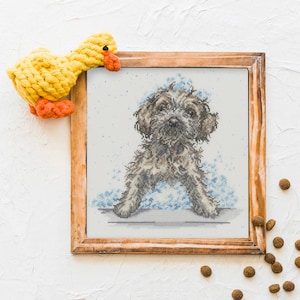 May include: A framed cross-stitch embroidery of a brown and white dog with blue and white water droplets around it. The dog is sitting and looking at the viewer.