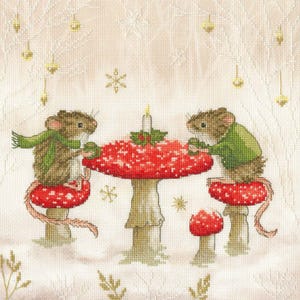 May include: Two mice wearing scarves and sweaters sit at a table made of a red and white mushroom. A lit candle sits in the center of the table, and the table is surrounded by a white background with snowflakes.